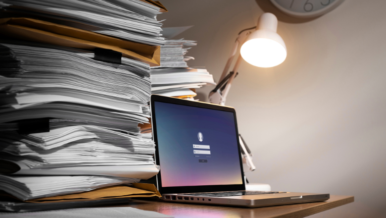 Laptop zwischen Papierstapeln als Symbol für die Verfahrensdokumentation in der Buchhaltung.