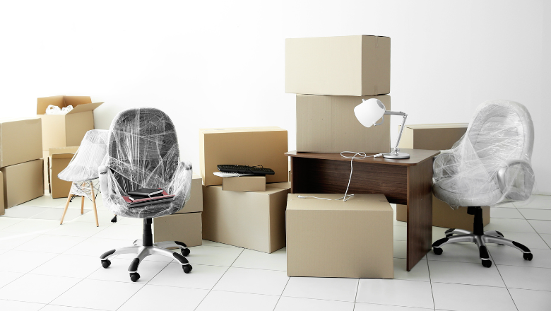 Umzugssituation im Büro mit Kartons, eingepackten Bürostühlen und einem Schreibtisch – symbolisch für Werteverzehr und Abschreibung. Keyword: Absetzung für Abnutzung AfA.