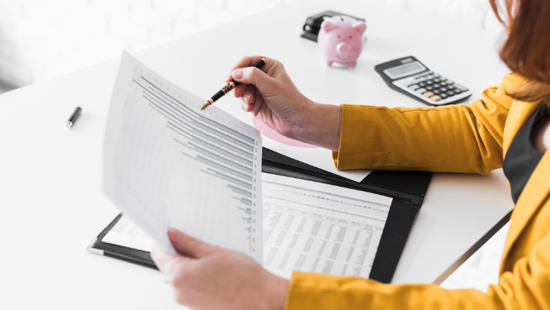 Frau analysiert Finanzdiagramme und Unterlagen zur Debitorenbuchhaltung am Schreibtisch.