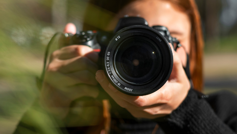 Freiberufler Frau mit Kamera fotografiert in der Natur – steht exemplarisch für kreative Freiberufler, etwa aus Fotografie, Design oder Medien.