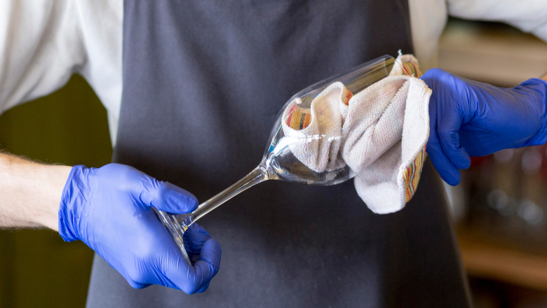 Glas wird von einer Person mit Handschuhen poliert – steht exemplarisch für Tätigkeiten im Minijob vs.Midijob.